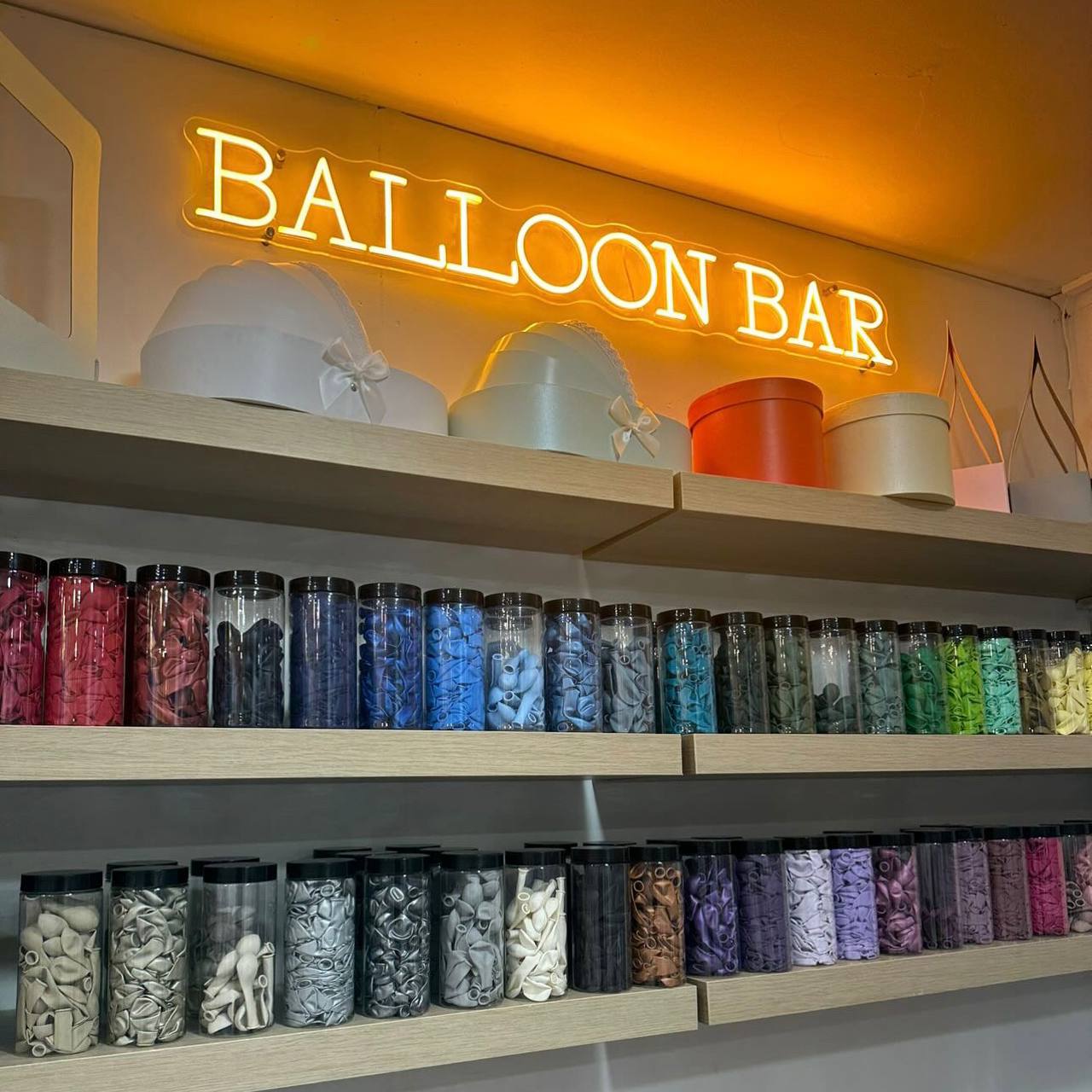 Shelves with colorful balloons and a neon 'Balloon Bar' sign.